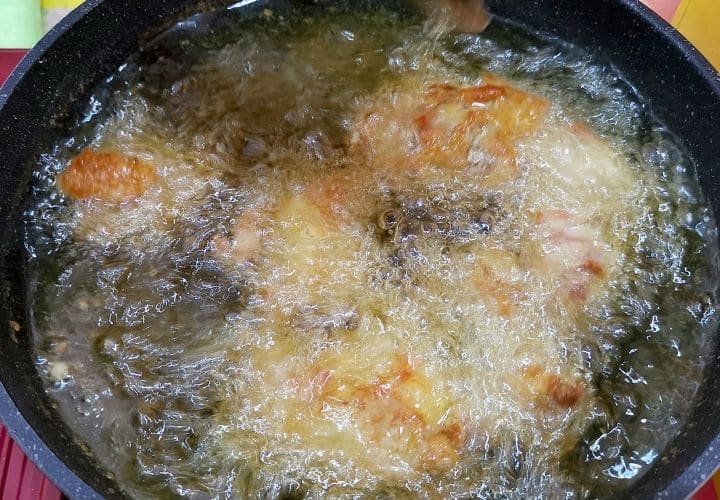 Chicken frying in a cast iron skillet.