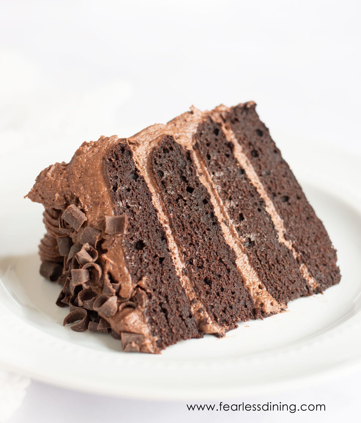 A gluten free chocolate cake slice on a white plate.