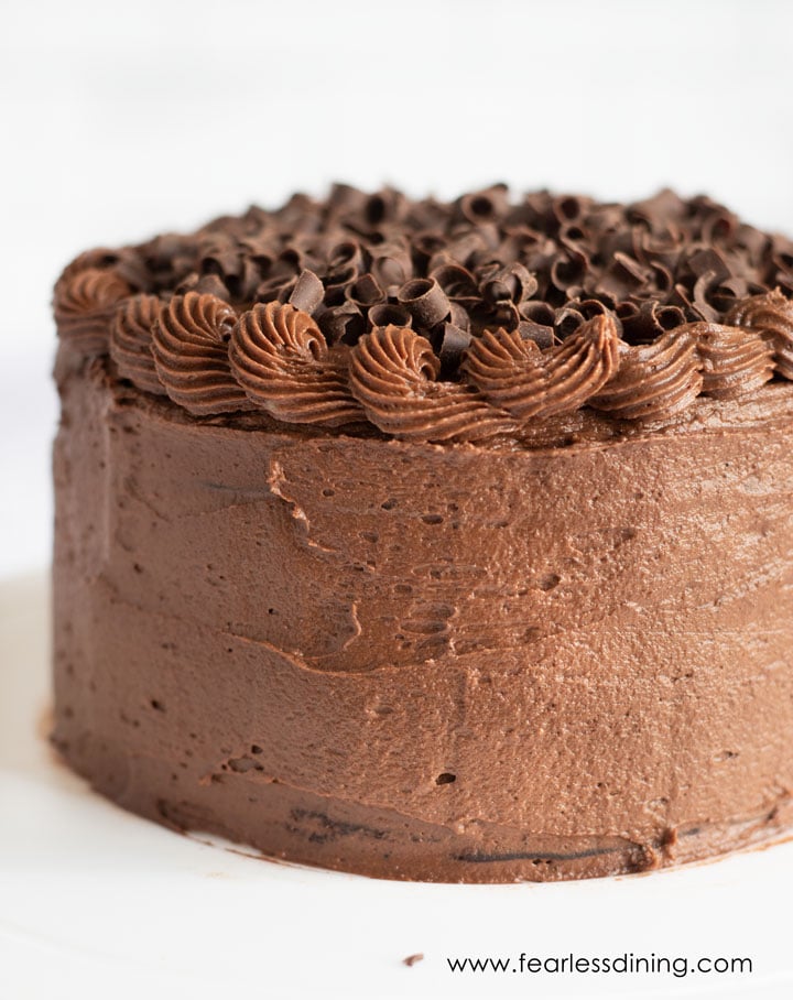 A whole chocolate frosted cake on a white plate.