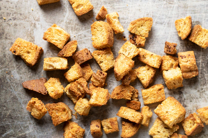 Gluten free croutons on a metallic cookie sheet.