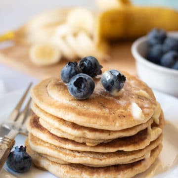 A stack of gluten free pancakes with blueberries and butter on top.