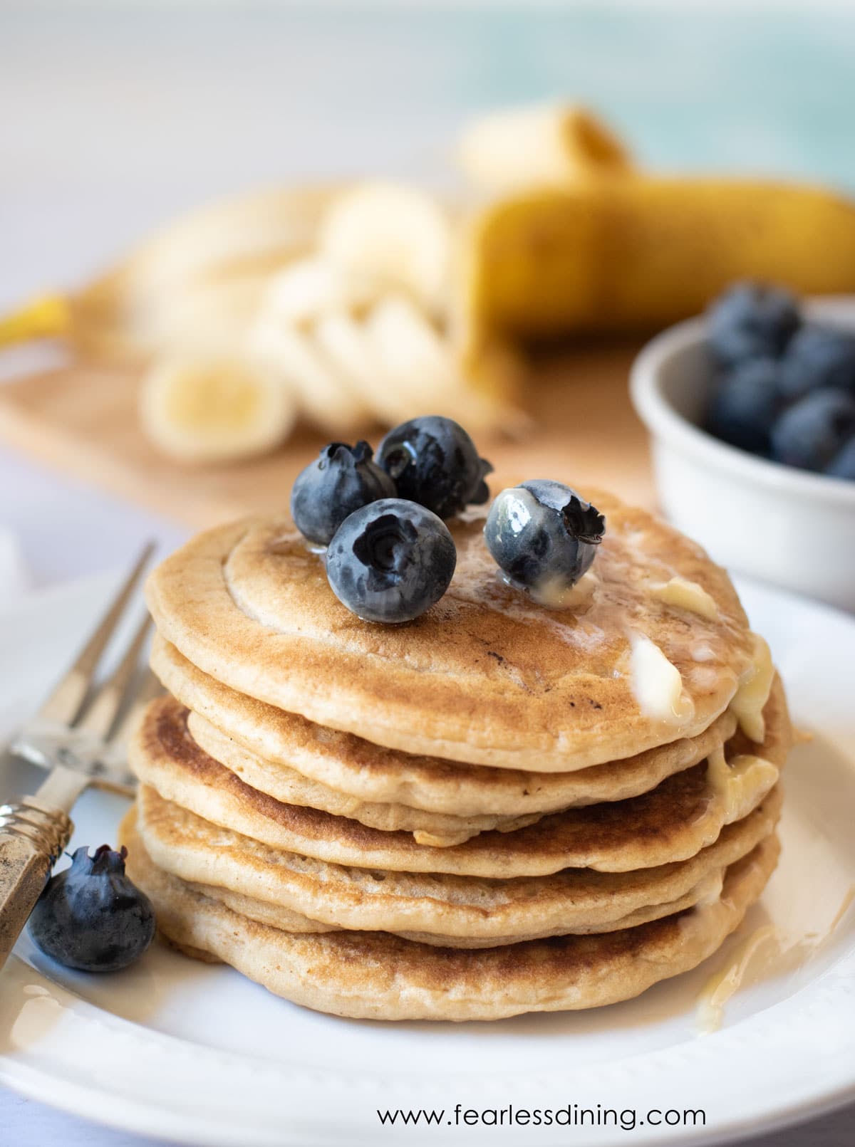 A stack of gluten free pancakes with blueberries and butter on top.