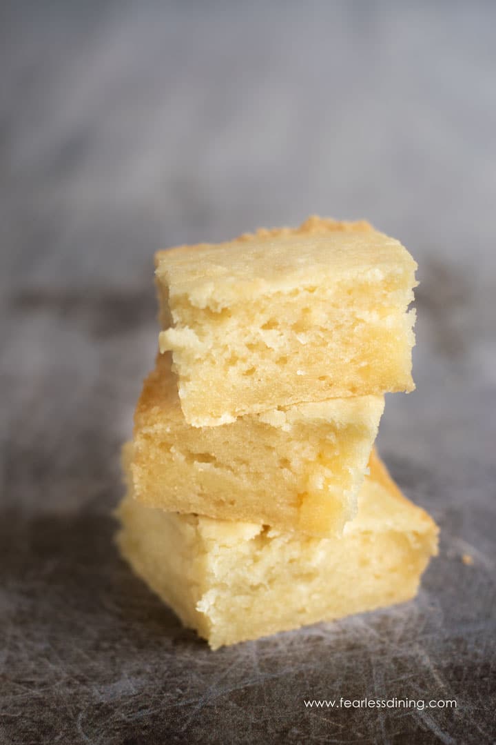 A stack of 3 butter mochi on a cookie sheet.