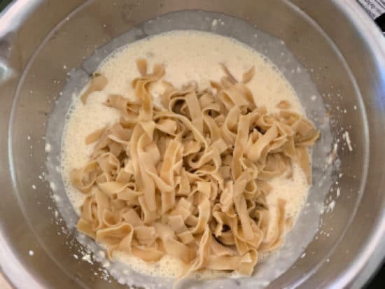Adding the noodles to the kugel ingredients.