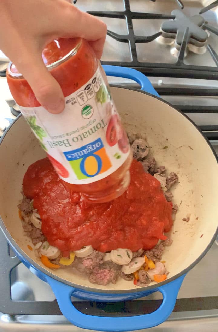 Pouring pasta sauce into a pot.