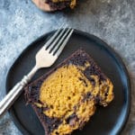 A slice of chocolate pumpkin cake on a dark wooden plate.