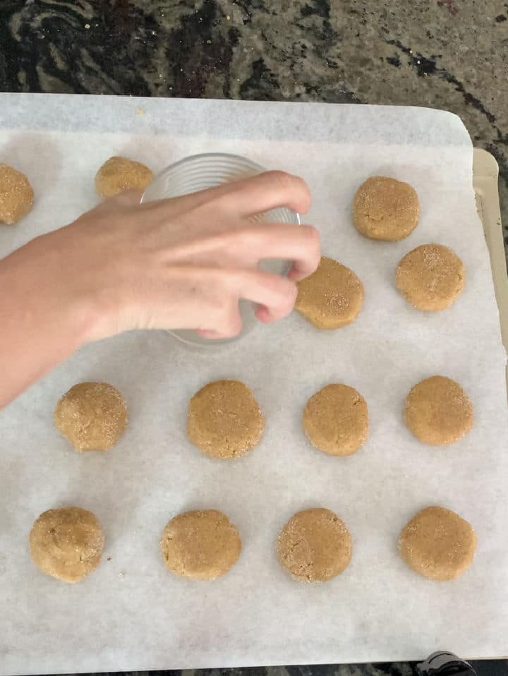 Smooshing cookie dough balls flat.