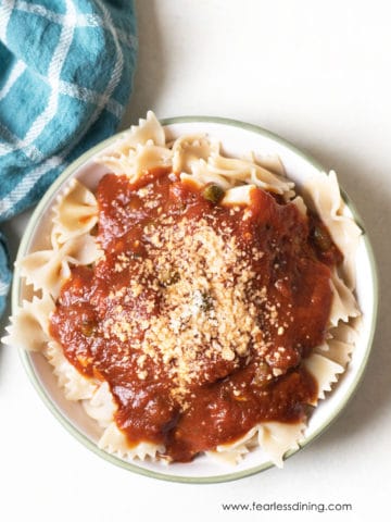 A bowl of gluten free bowtie pasta topped with homemade marinara sauce.