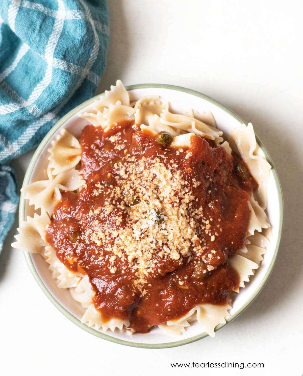 A bowl of gluten free bowtie pasta topped with homemade marinara sauce.