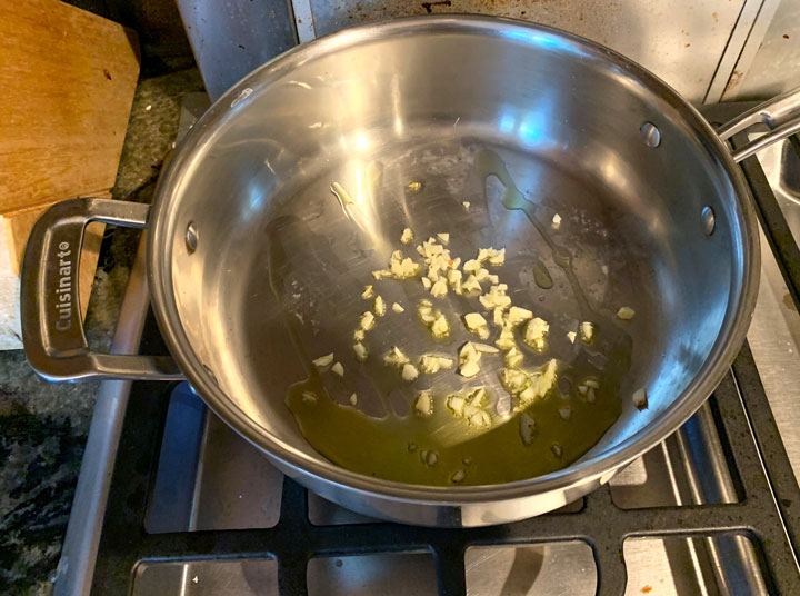 Sauteing garlic and oil in a large pan.