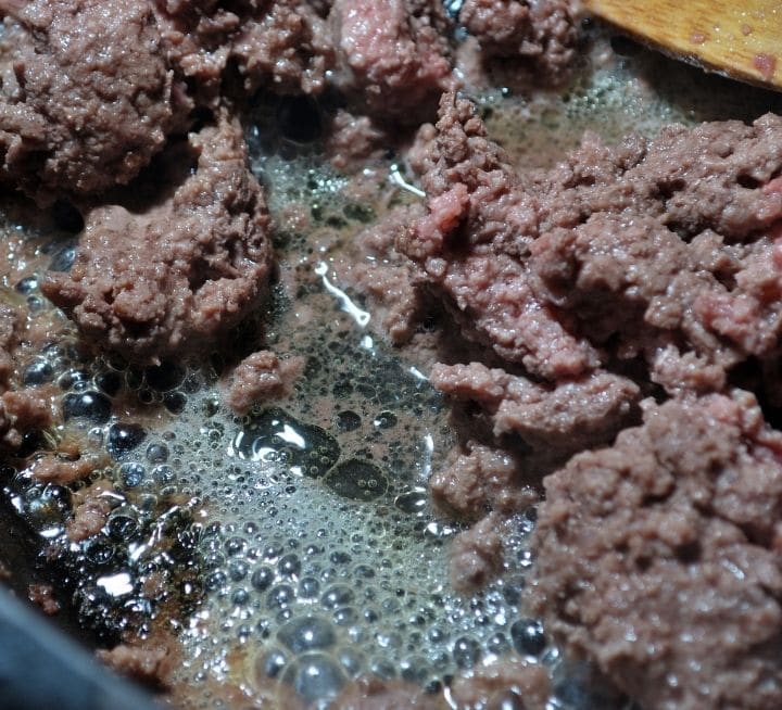Browning ground meat in a cast iron skillet.