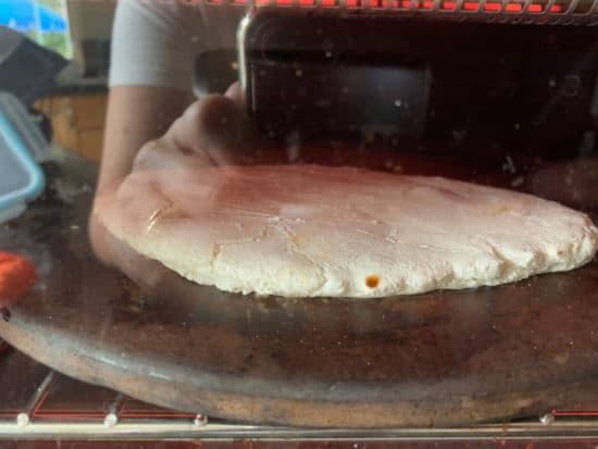 Flatbread cooking on a pizza stone in the oven.