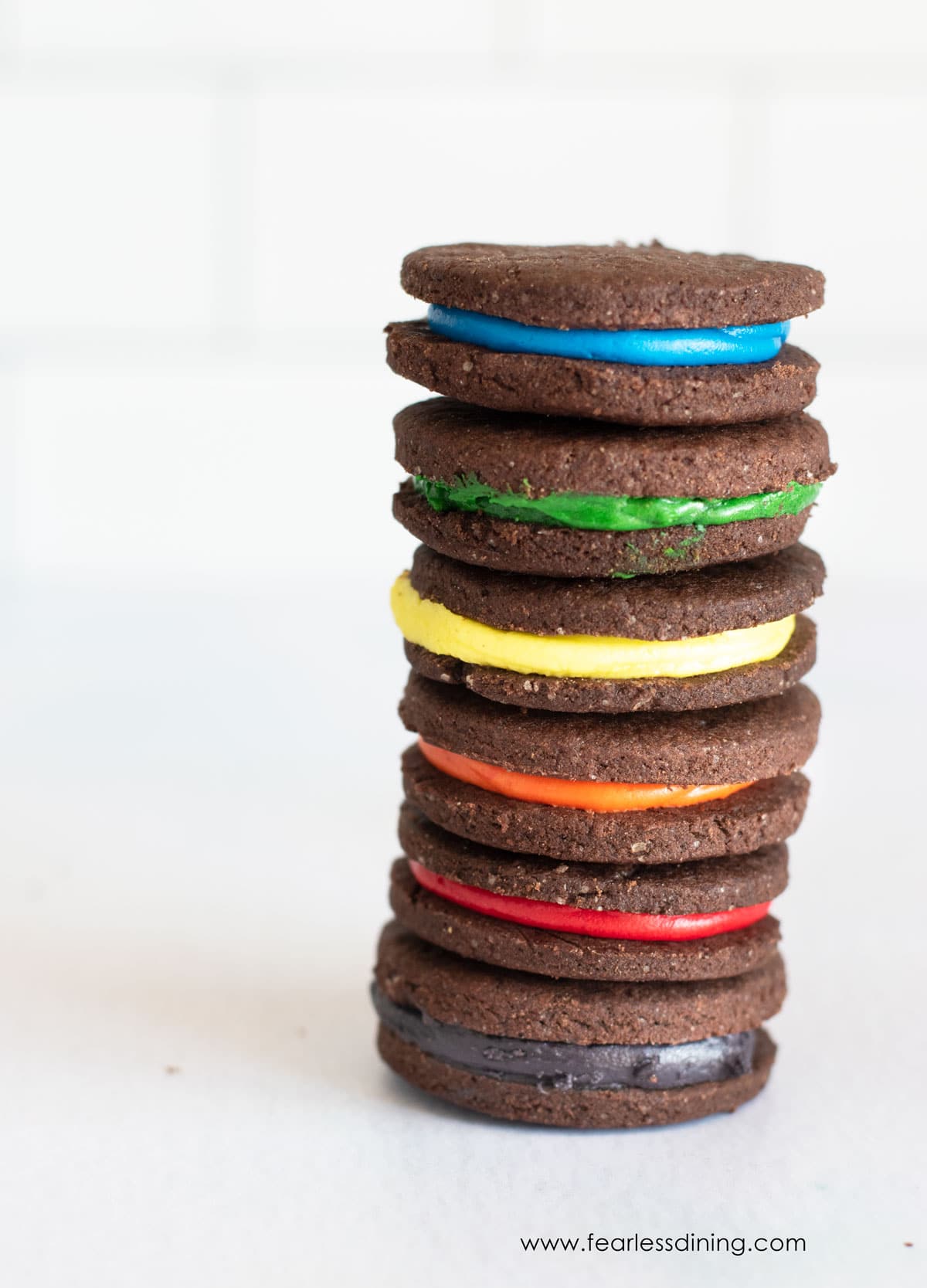 A tall stack of gluten free rainbow oreo cookies.