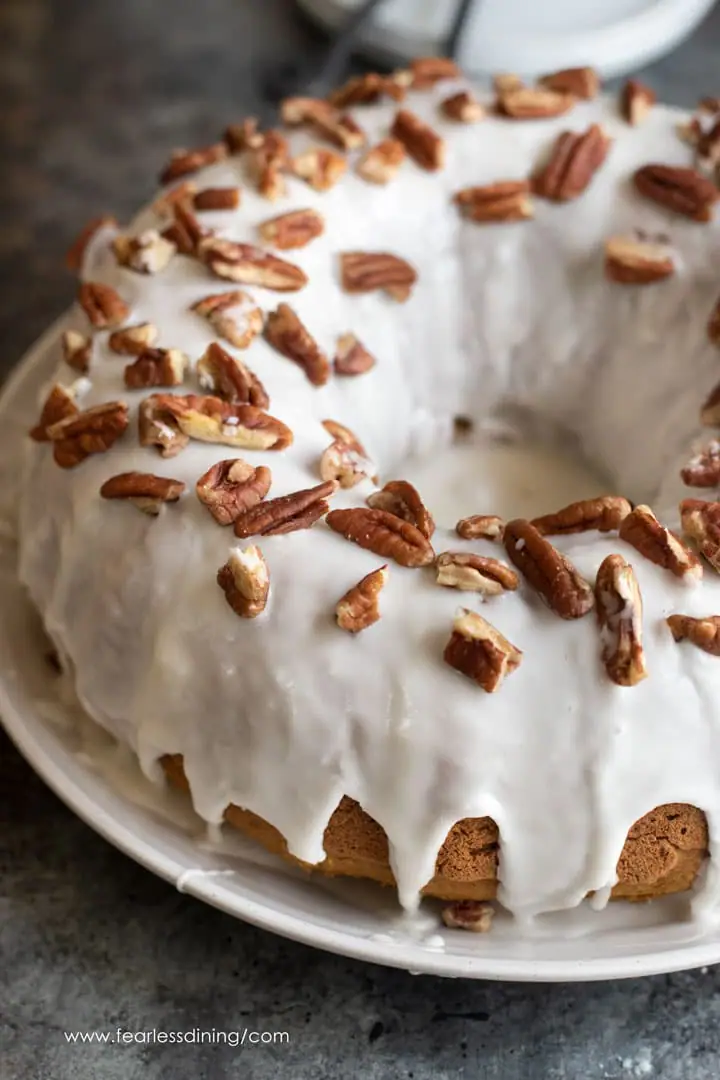 an iced pumpkin bundt cake topped with chopped pecans