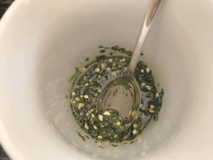 a small bowl of herbs, garlic, and oil