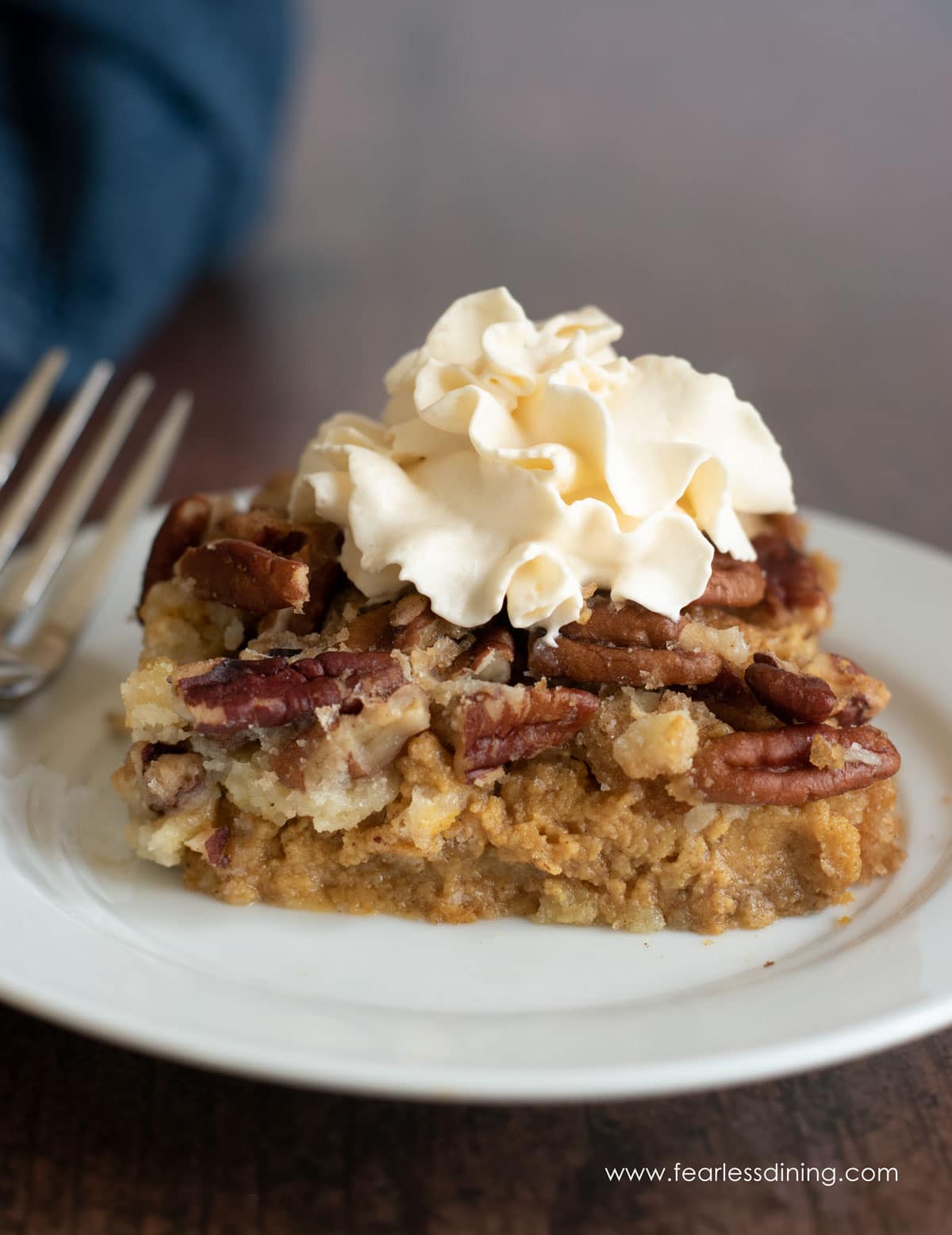 A slice of gluten free pumpkin dump cake with pumpkin spice whipped cream.