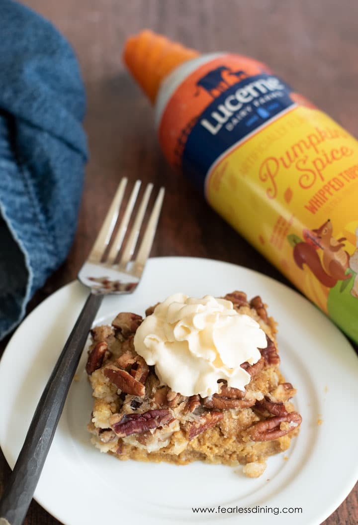 A slice of pumpkin dump cake next to the whipped cream bottle.