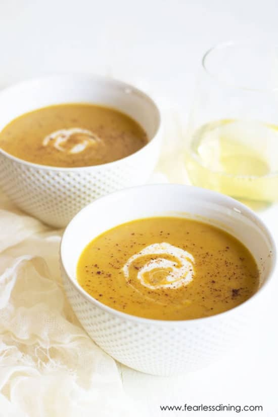 Two bowls of butternut squash soup. They are garnished with cream.
