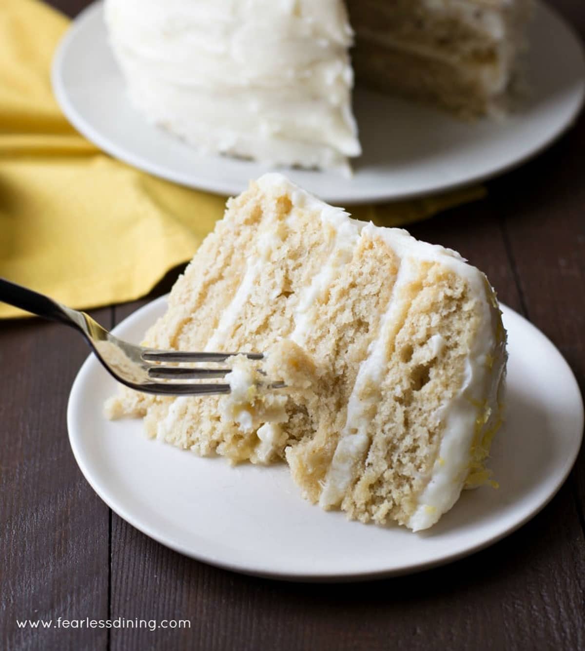 A fork slicing into a piece of lemon cake.