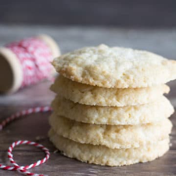 A stack of five sugar cookies on a wooden platter.