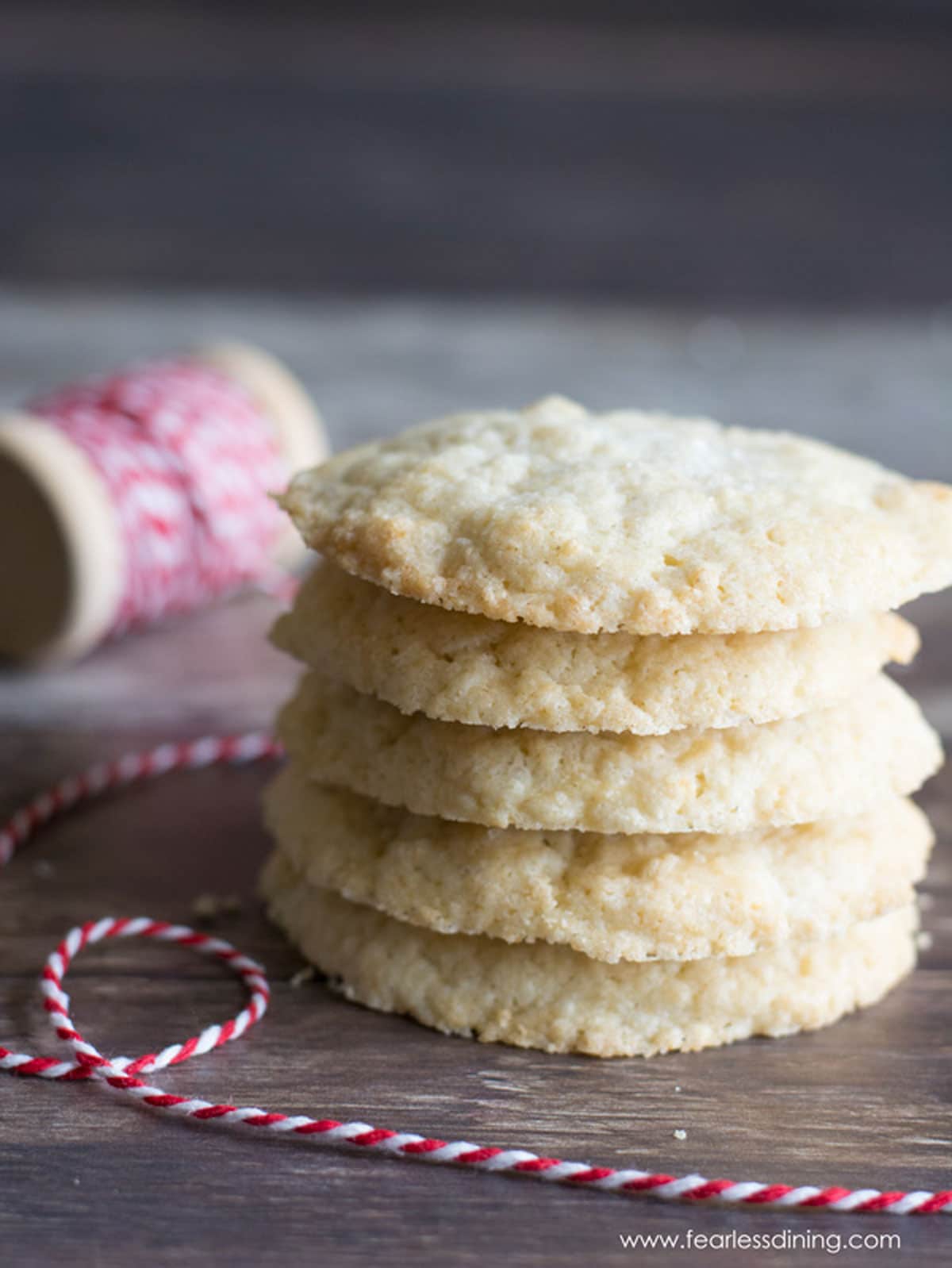 A stack of five sugar cookies next to a spool of white and red striped string.