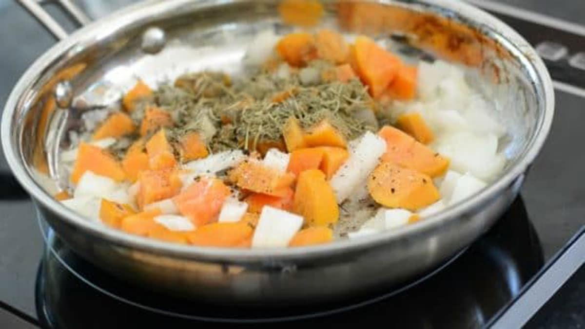 Persimmon onion and herbs cooking in a frying pan.