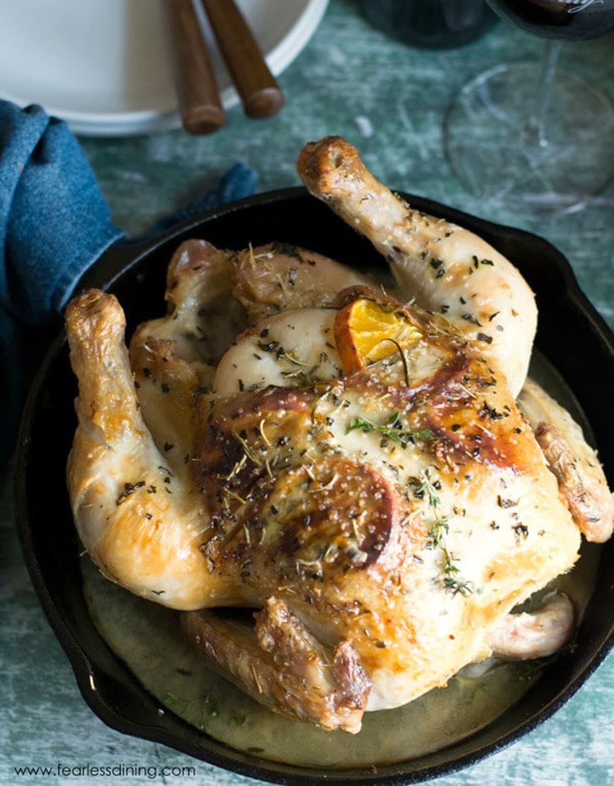 The top view of a roasted whole chicken in a cast iron pan.