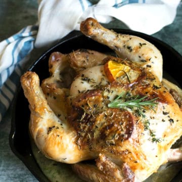 A whole roasted chicken in a cast iron skillet.