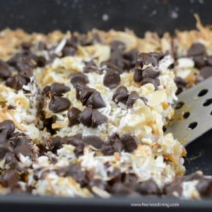 Scooping out a slice of gingerbread 7 layer bars from the pan.