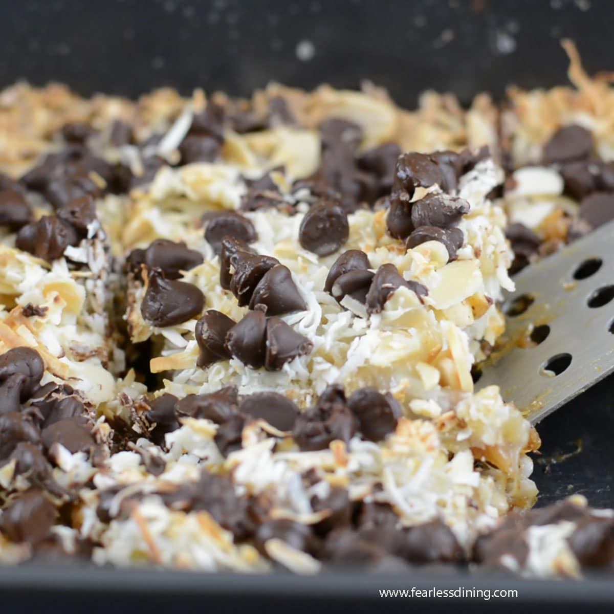 Scooping out a slice of gingerbread 7 layer bars with a spatula.