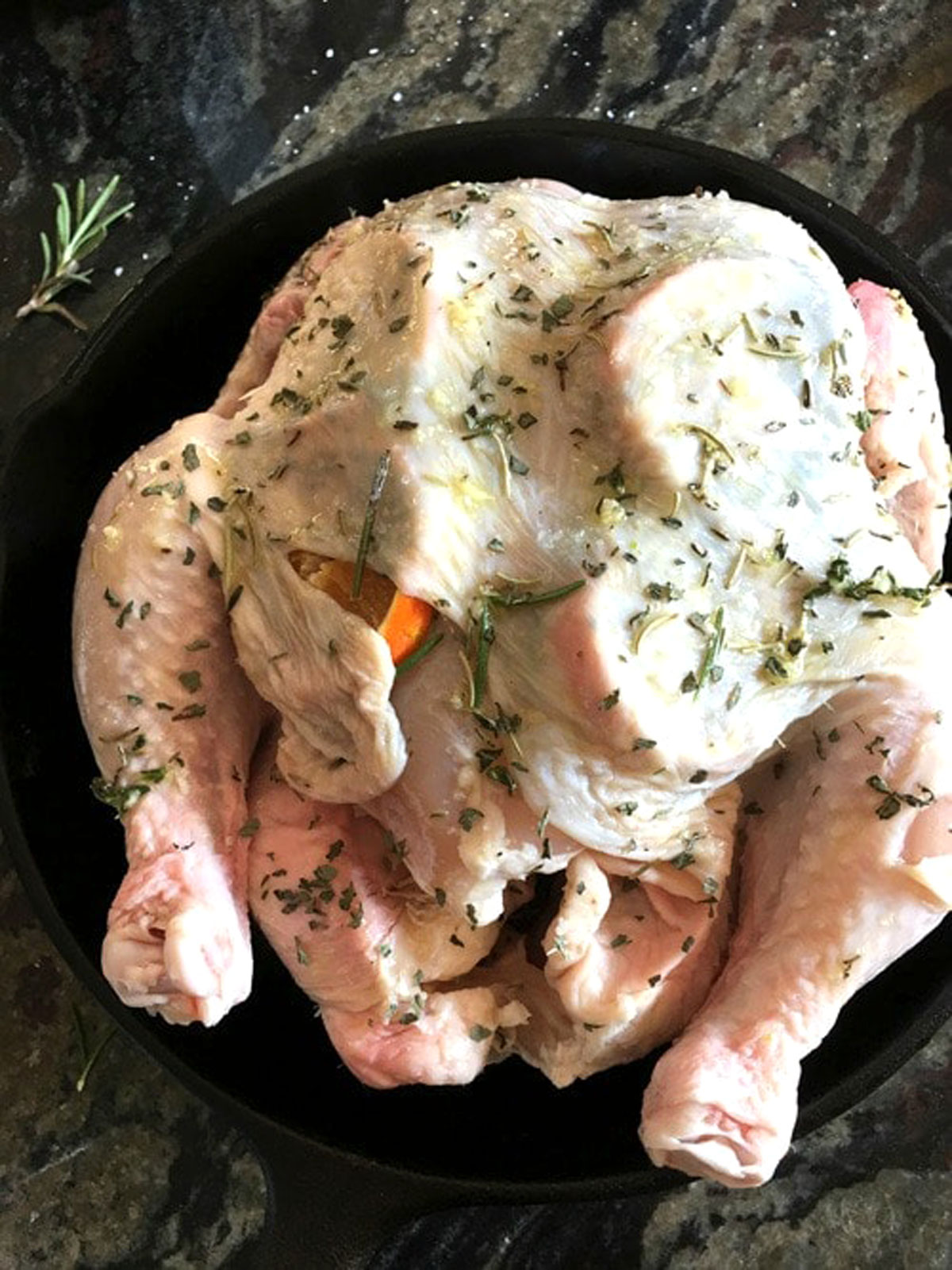 A raw chicken with fresh herbs under the skin.