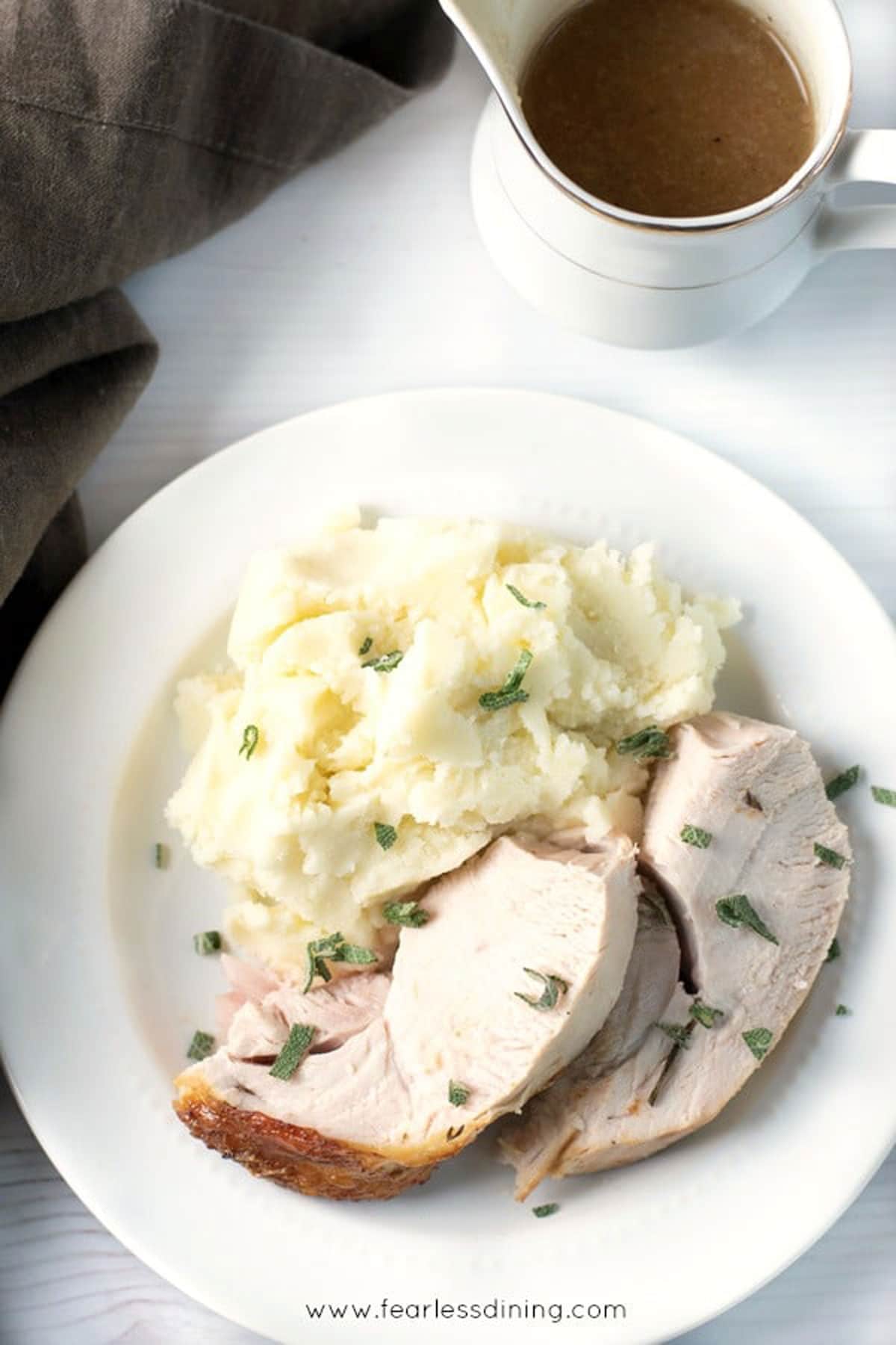 The cooked sliced turkey breast next to mashed potatoes on a plate.