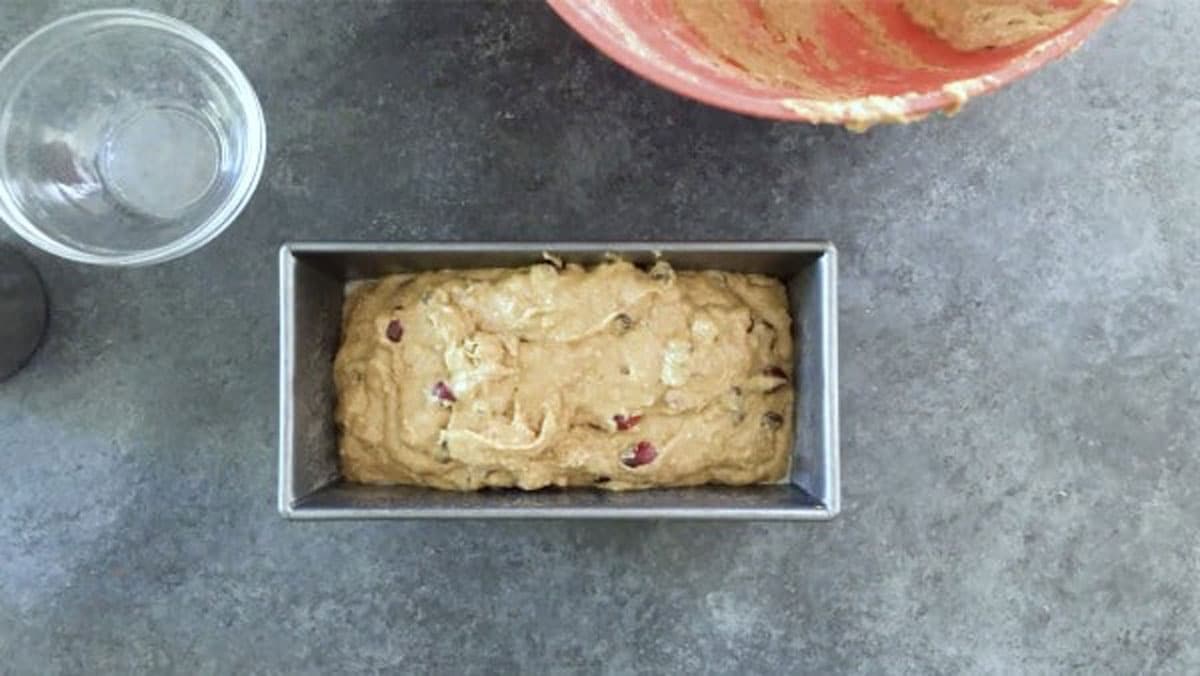 The cranberry bread batter in a bread loaf tin.