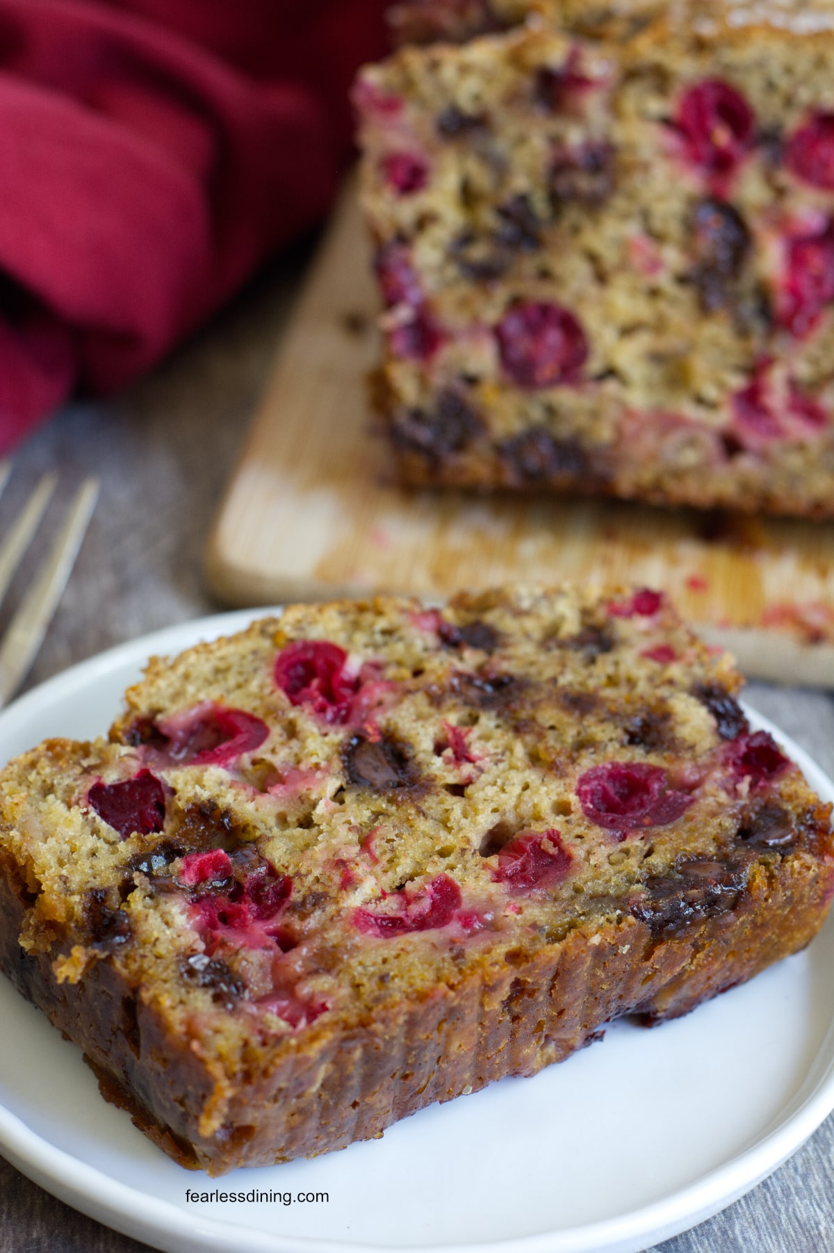 A closeup of a slice of the cranberry bread on a small white plate.