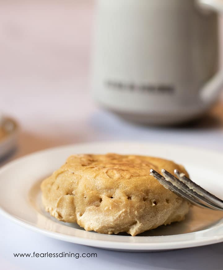 An English muffin on a plate with a fork.