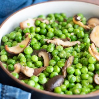 a close up of a bowl of ginger peas with shiitake mushrooms