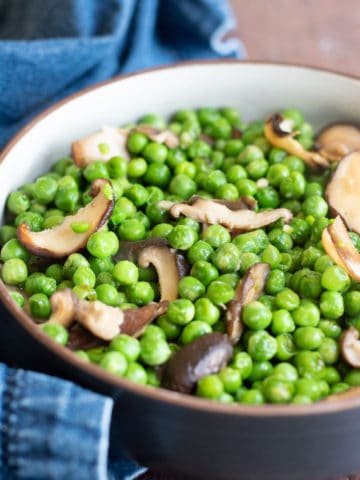 a close up of a bowl of ginger peas with shiitake mushrooms