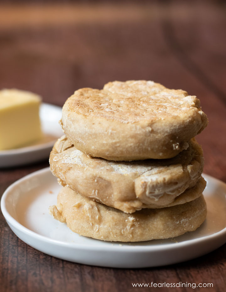 A stack of three gluten free English muffins on a plate.