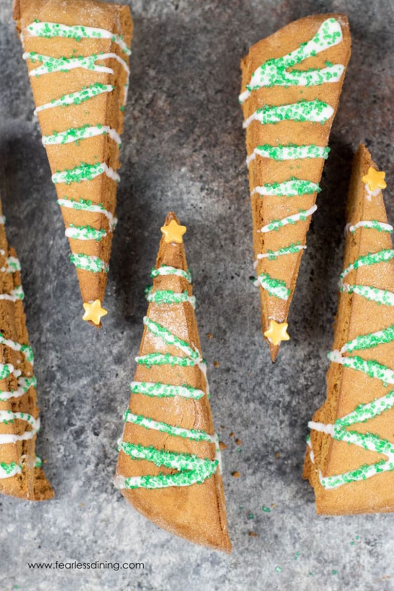 Gluten free gingerbread biscotti decorated like Christmas trees on a pan.