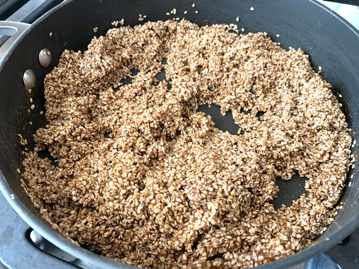 Sesame seeds mixed with the honey mixture in a pan.