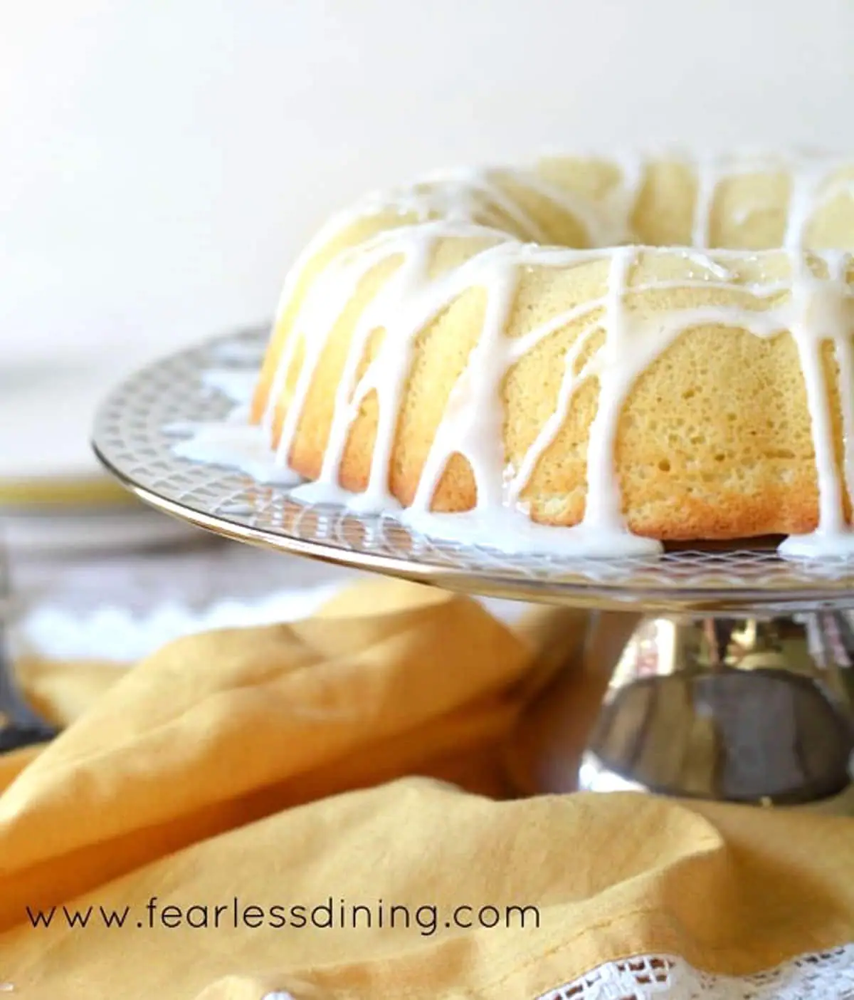 the side view of an iced lemon bundt cake on a platter