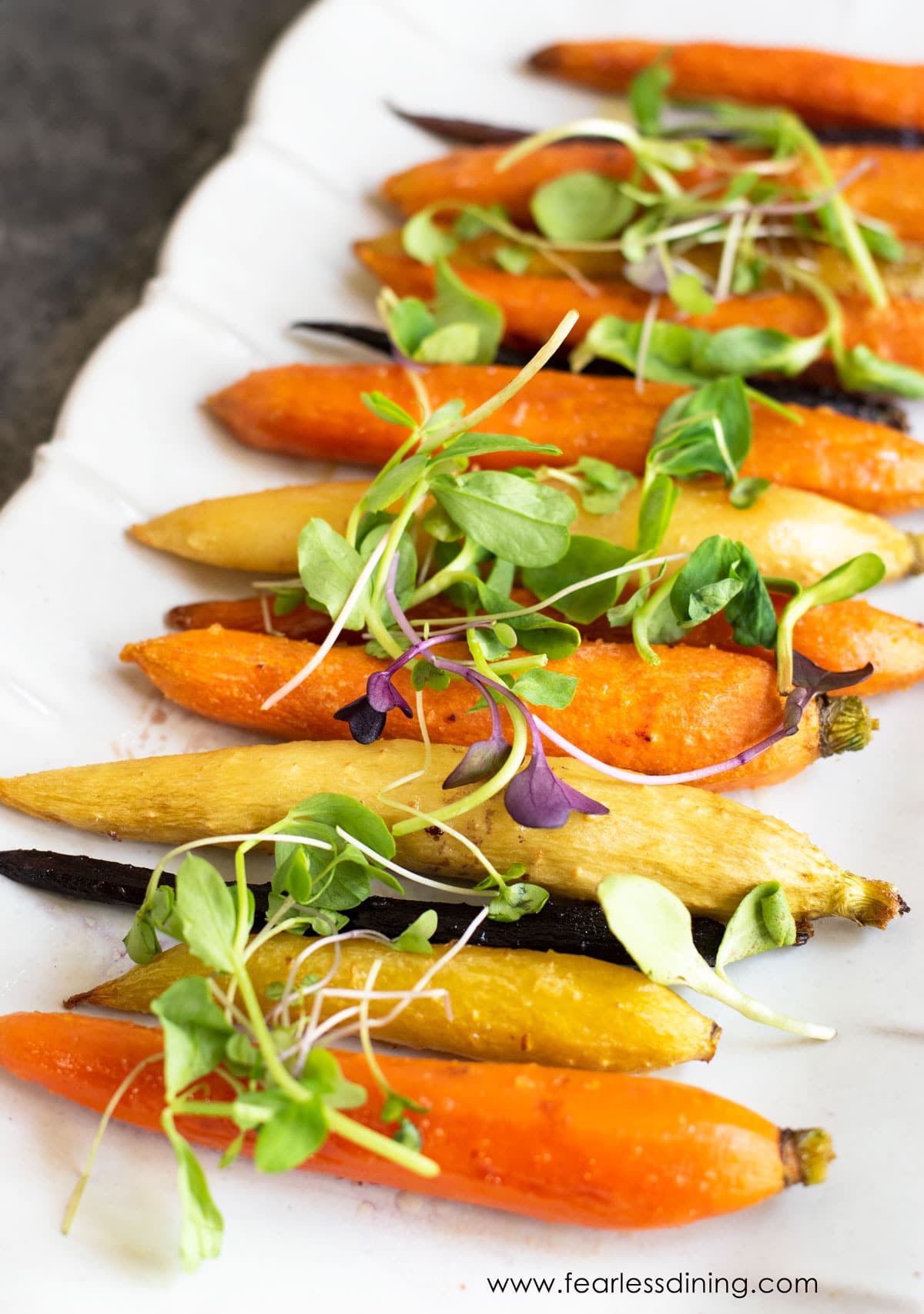 a platter with whole maple roasted carrots, topped with sprouts