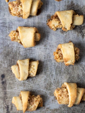 Baked rugelach on a cookie sheet.