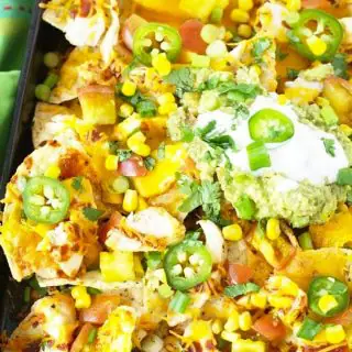 a close up of a tray of nachos topped with sour cream