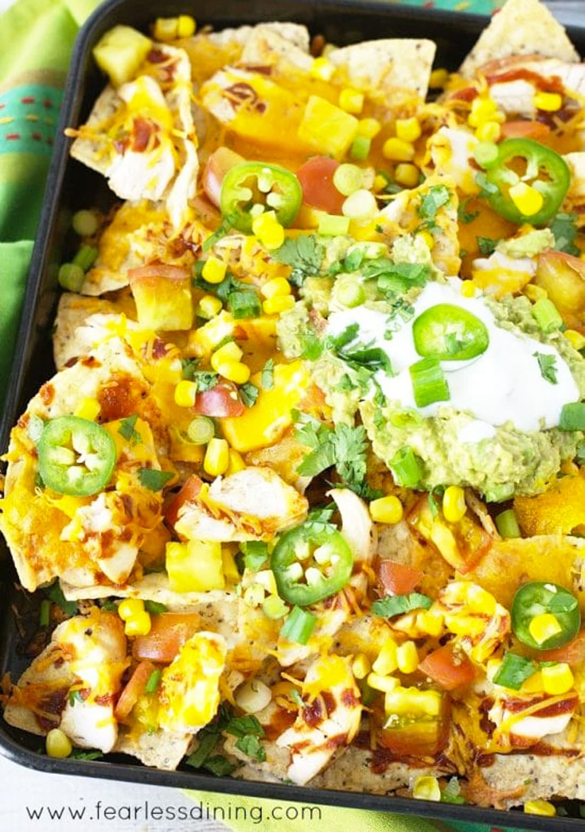 A close up of a tray of nachos topped with sour cream.