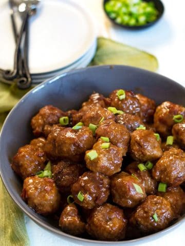 a large grey bowl full of meatballs. They are garnished with scallions