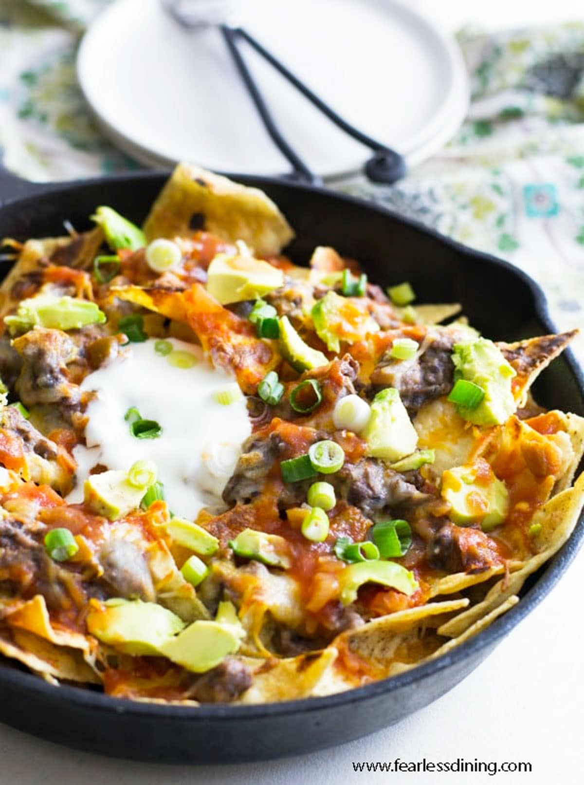 A cast iron skillet full of nacho bean dip nachos.