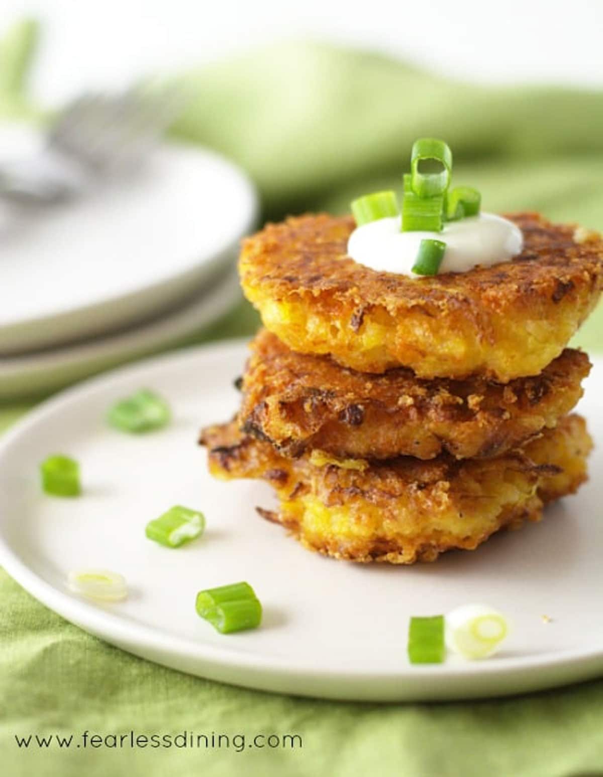 A stack of three fritters topped with sour cream.