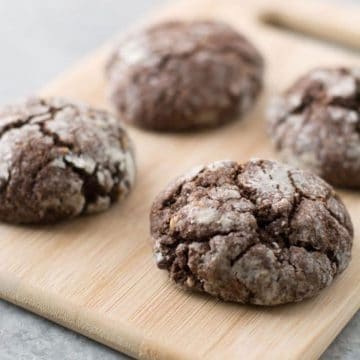 Chococolate crinkle cookies on a cutting board.