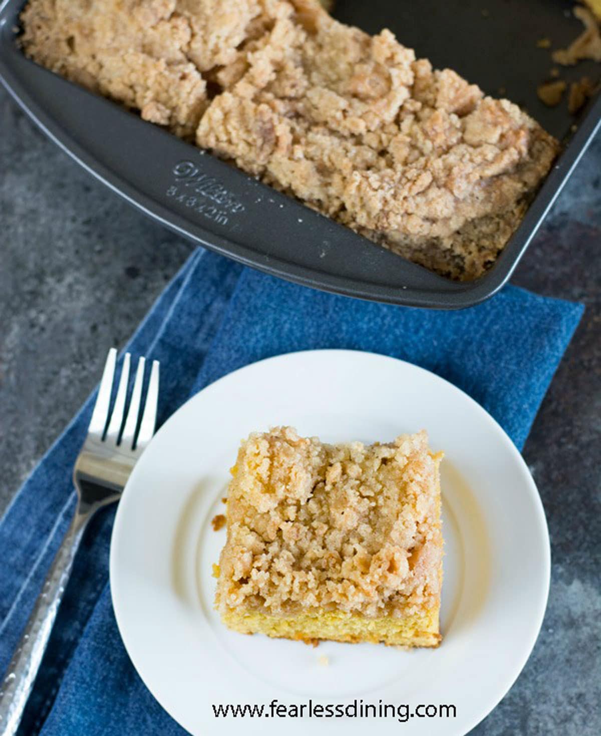 The top view of a slice of crumb cake next to the cake pan.